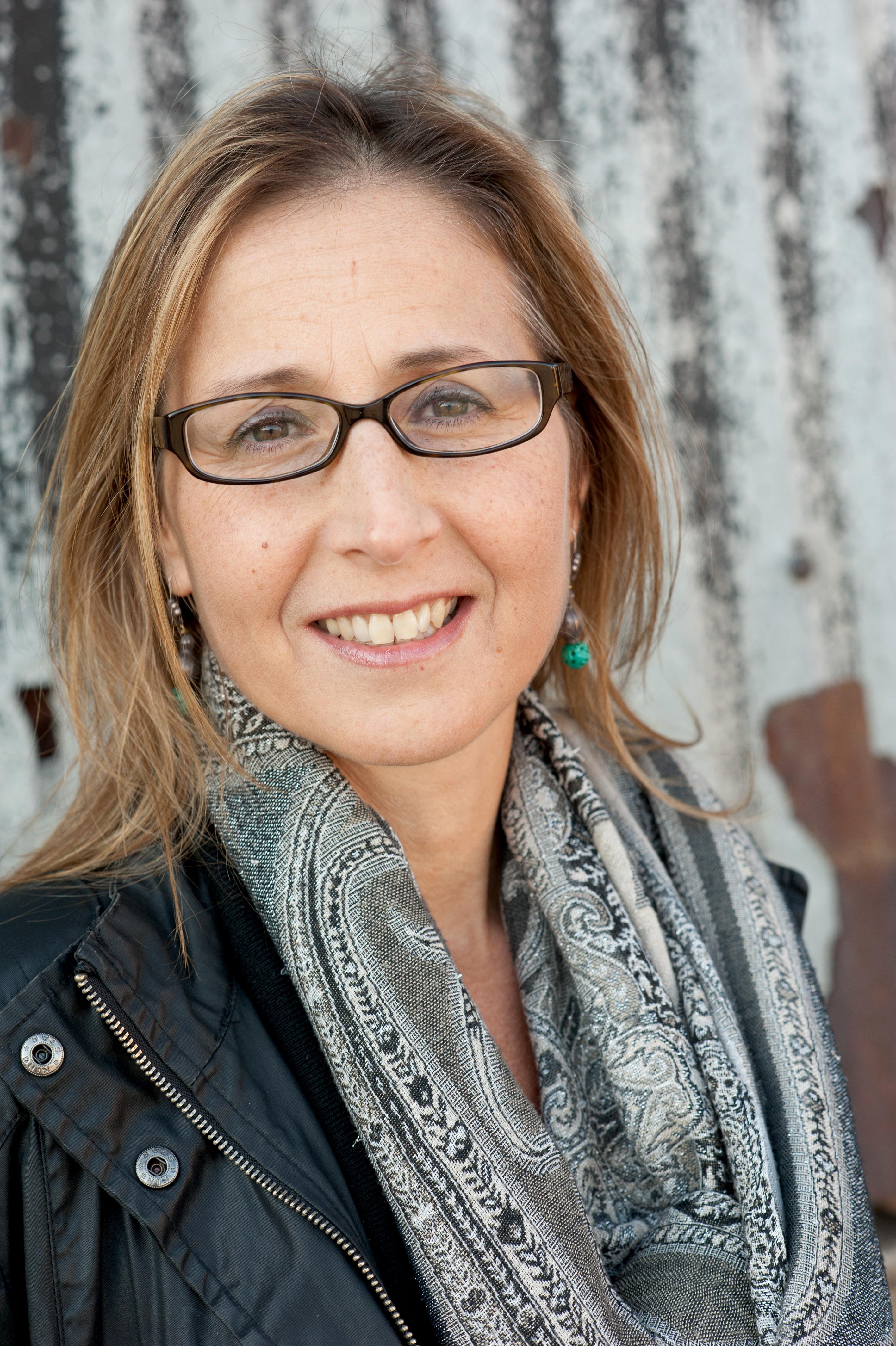 Lorena Luciano wears black glasses and has shoulder length blonde hair. She smiles at the camera directly.