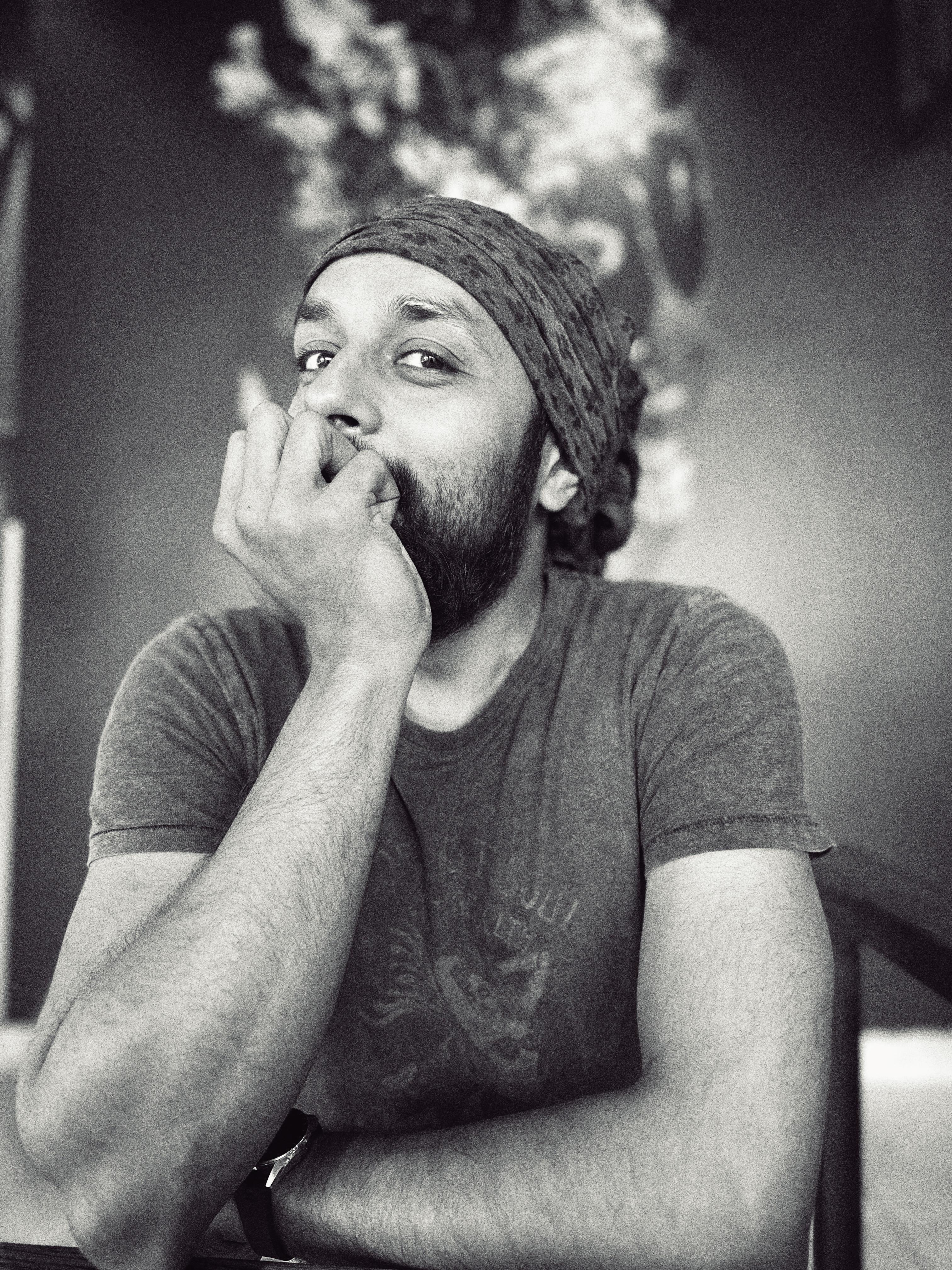 A black and white image of a bearded man, wearing a bandana, smiling into the camera.
