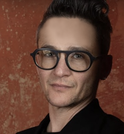 White guy with short dark hair, dark aviator-shaped glasses, and a black shirt