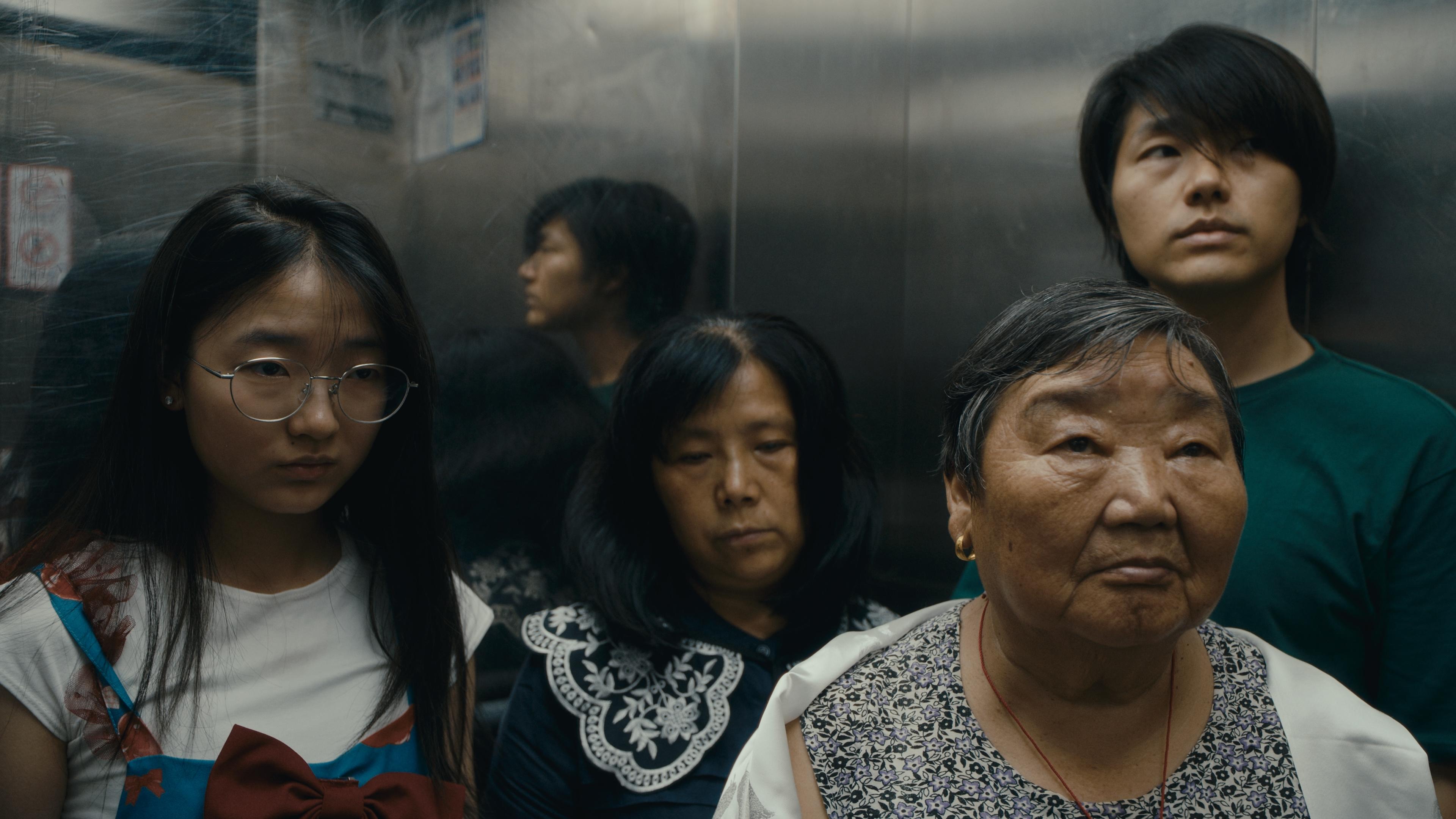 Four people wait in an elevator.