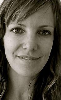 Katie Galloway looks at the camera and smiles. Portrait in black and white.