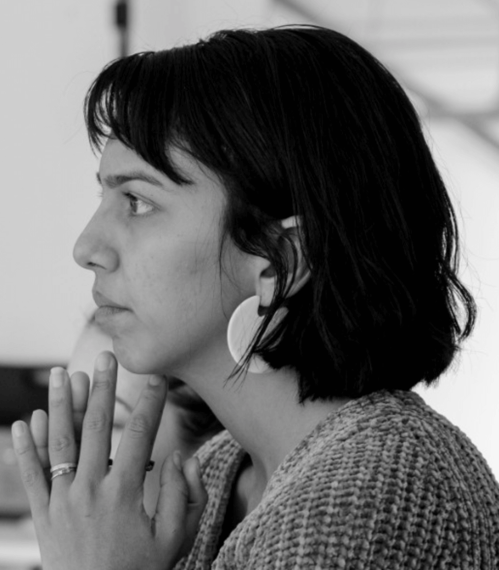 A woman with shoulder-length dark hair and bangs looks intently to the left with her chin resting lightly on her fingers. Headshot of Natalie Patillo