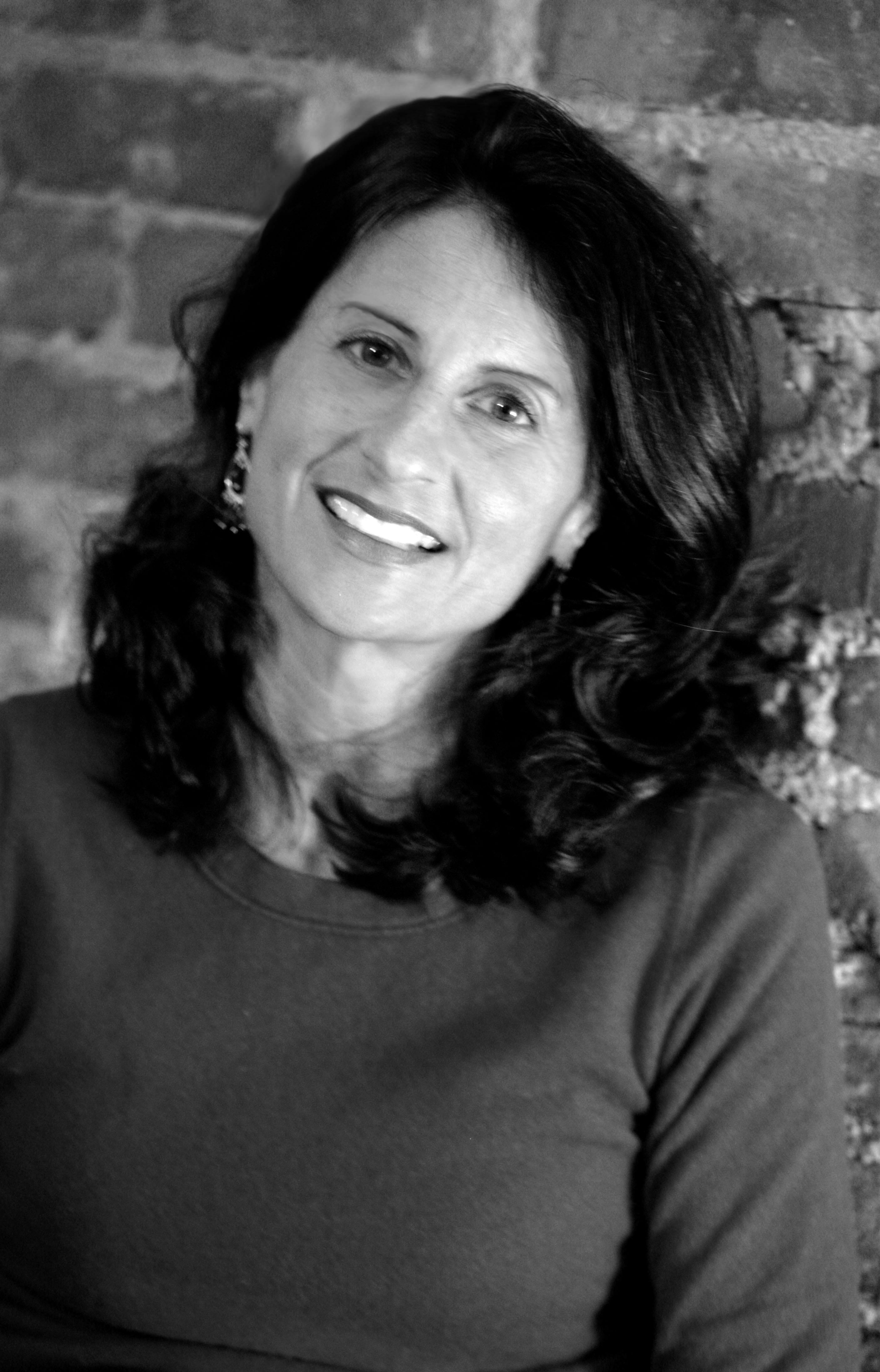 Jill Bauer looks at the camera and smiles. Black and White portrait.