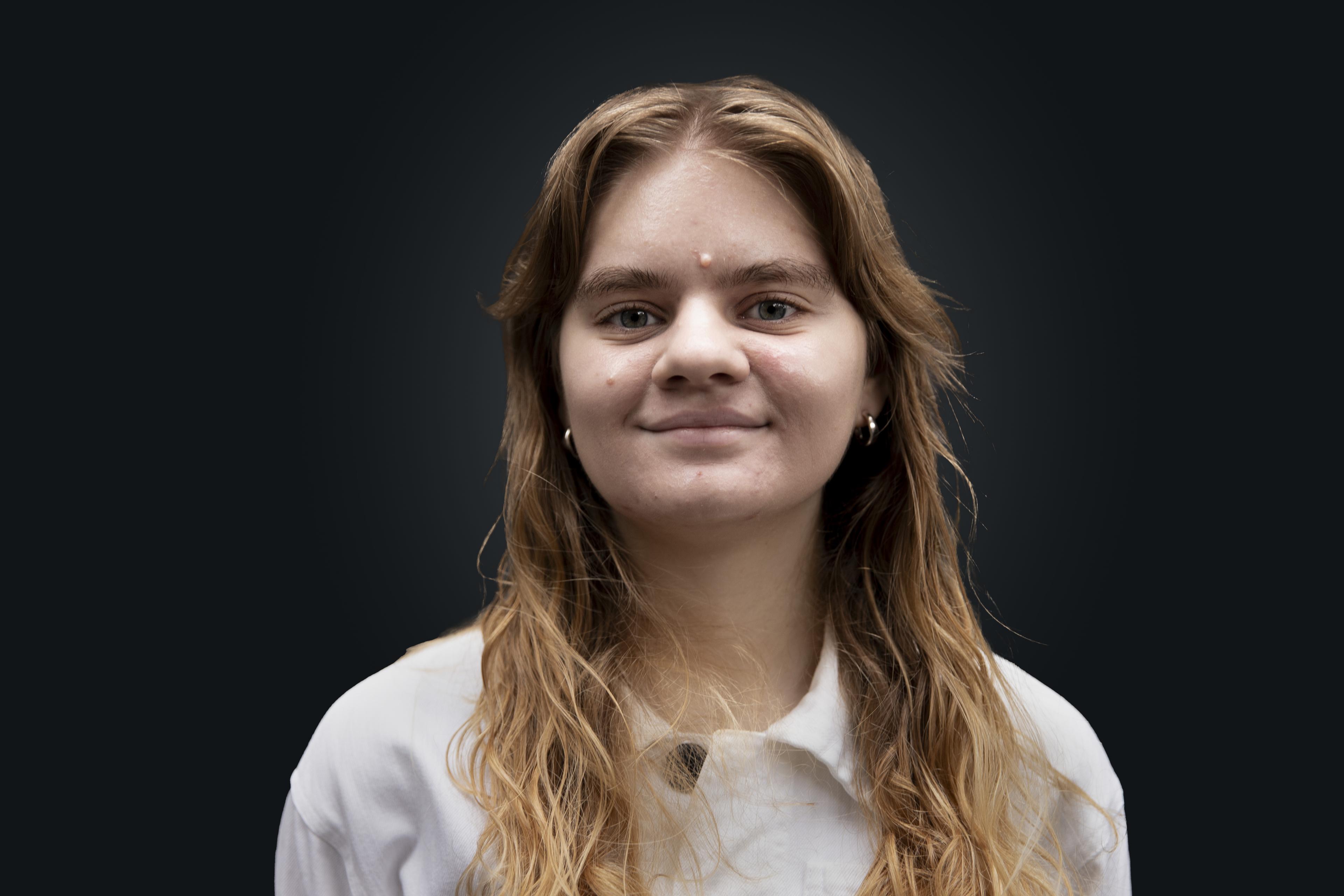 Communications Assistant Amelia Ray looks directly at the camera and smiles.