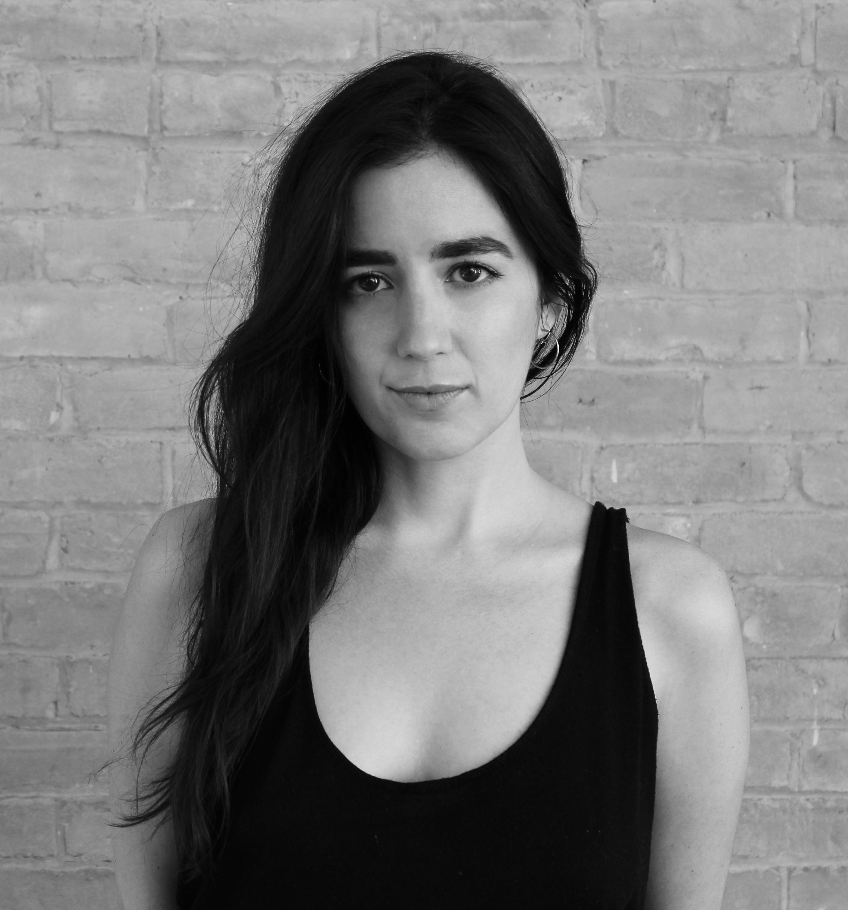 Robie Flores looks directly at the camera. Portrait in black and white.