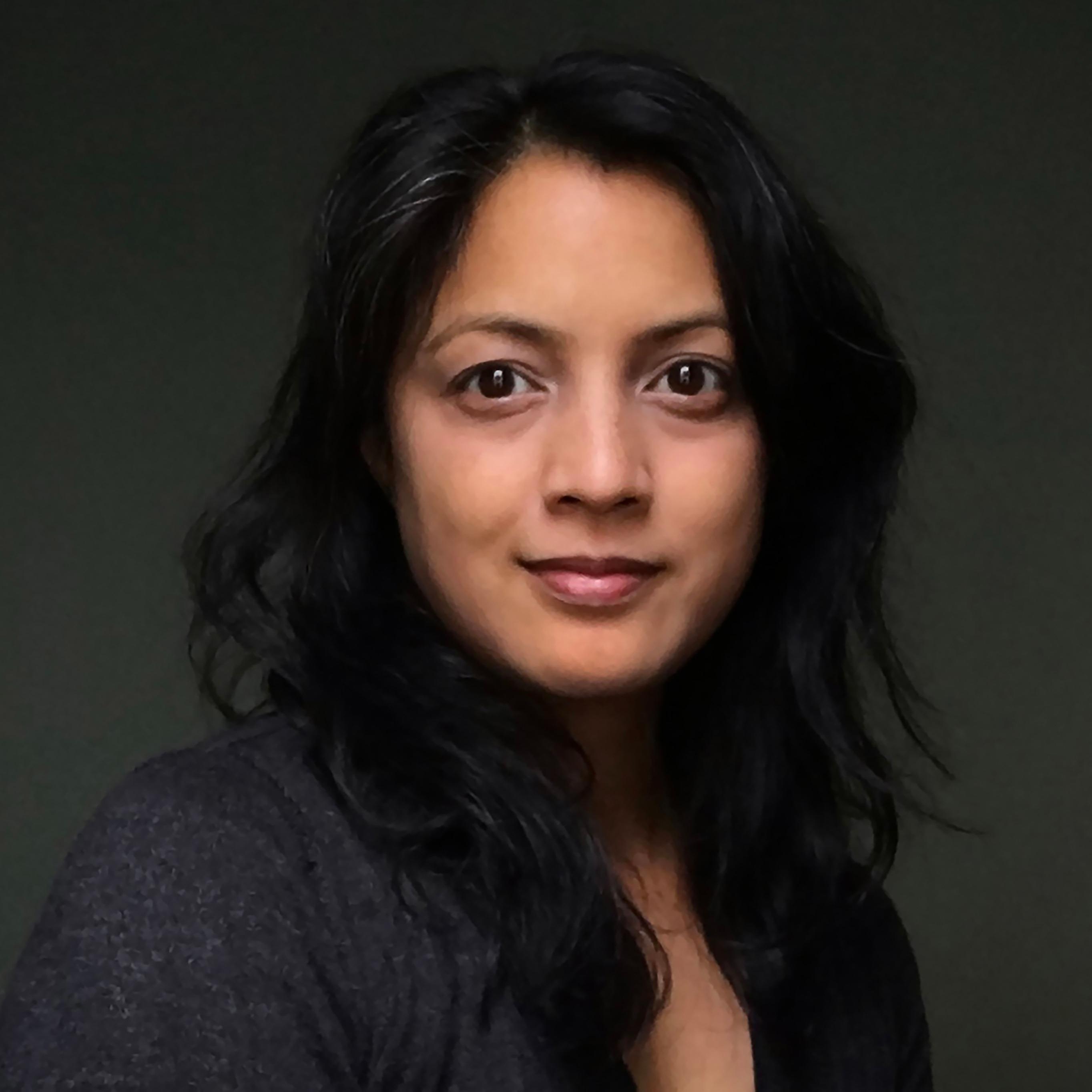 Director Karla Murthy is South Asian and Filipina woman with dark hair, brown eyes and skin, wearing a dark grey sweater.