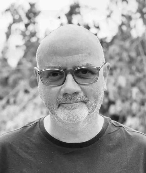 Simon Kilmurry looks at the camera and smiles. He is wearing glasses. Black and white portrait.