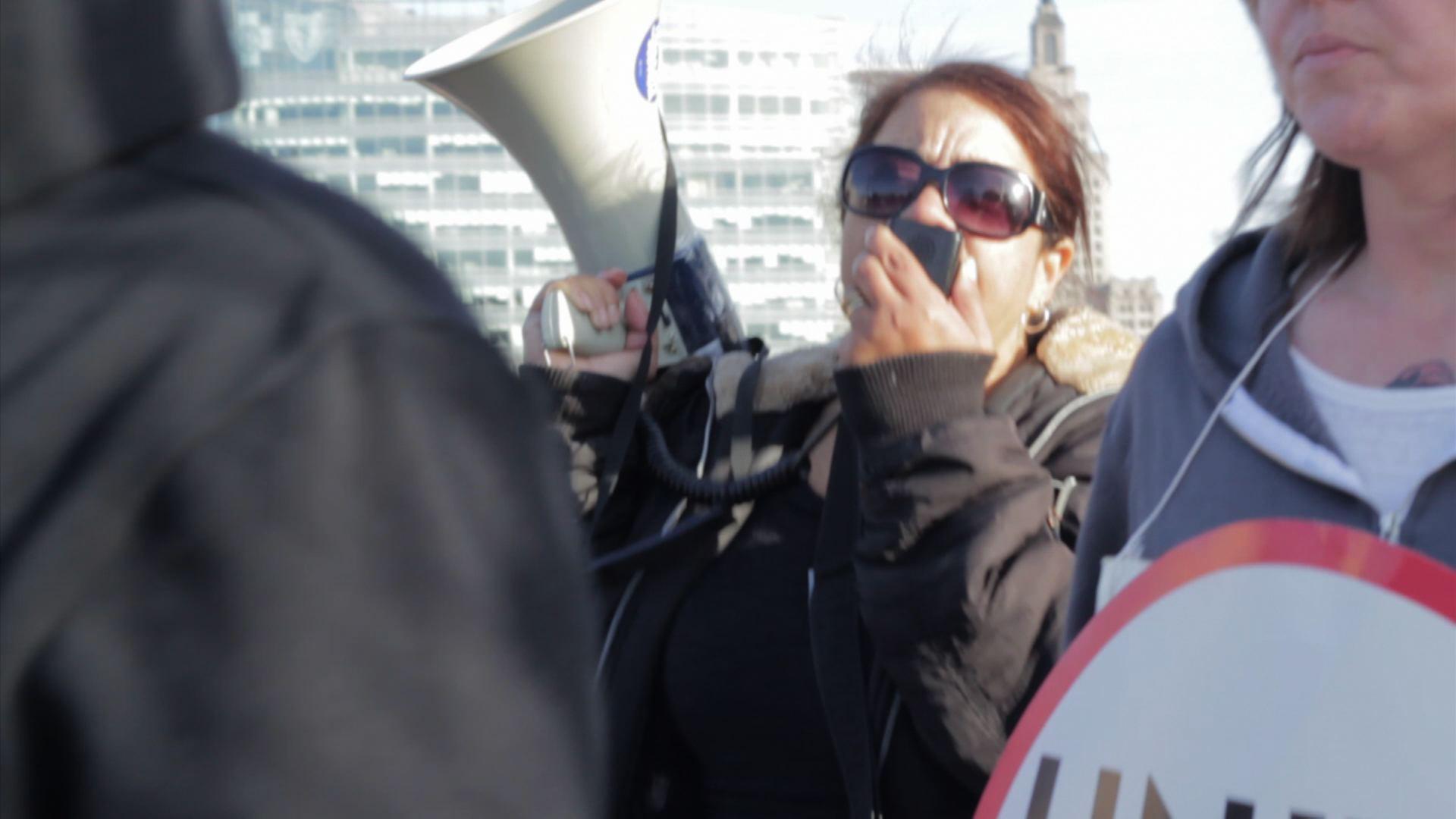 Woman holds bullhorn at rally.