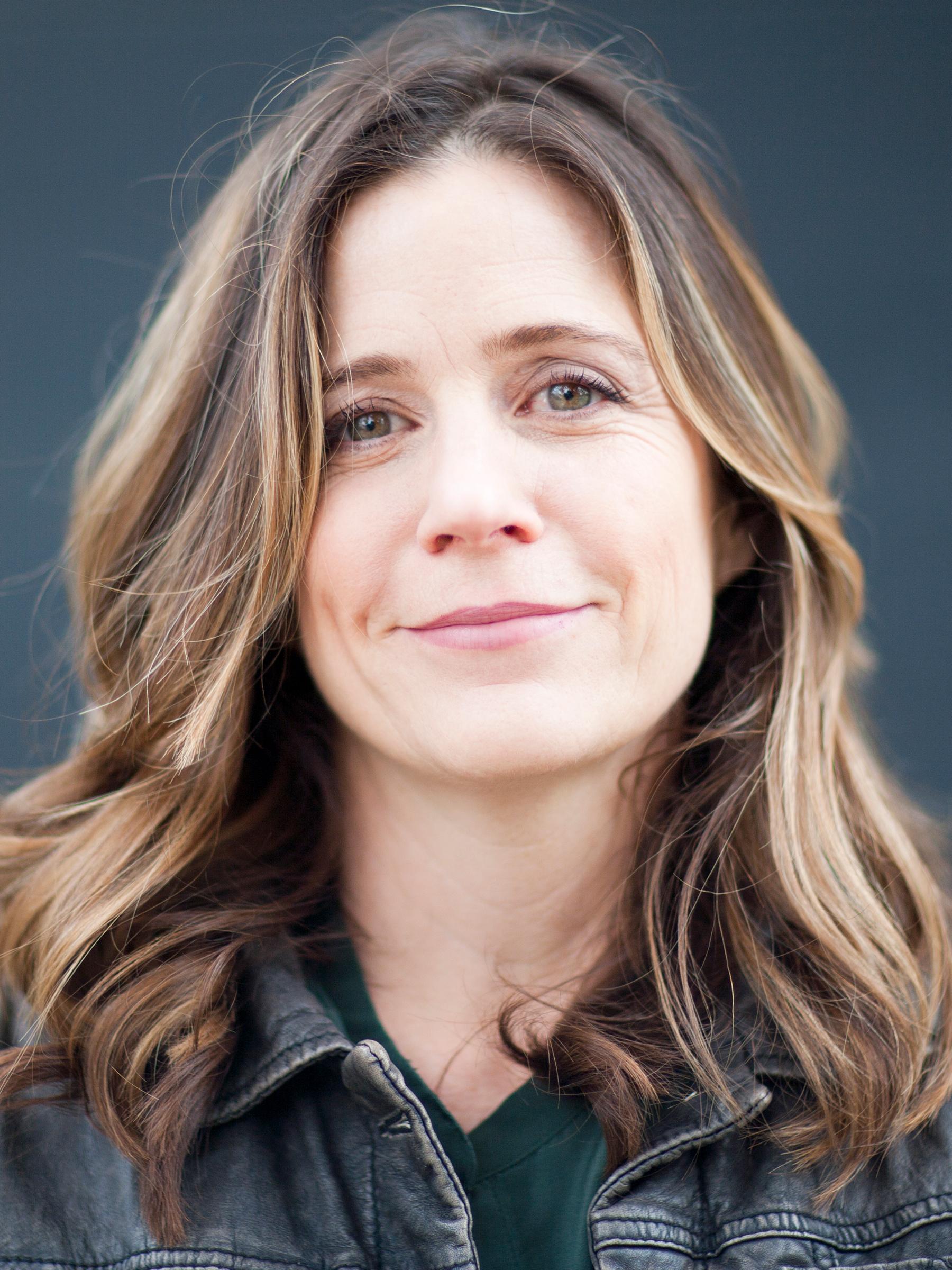 Tracy Droz Tragos with shoulder length brown hair smiles and looks directly ahead.