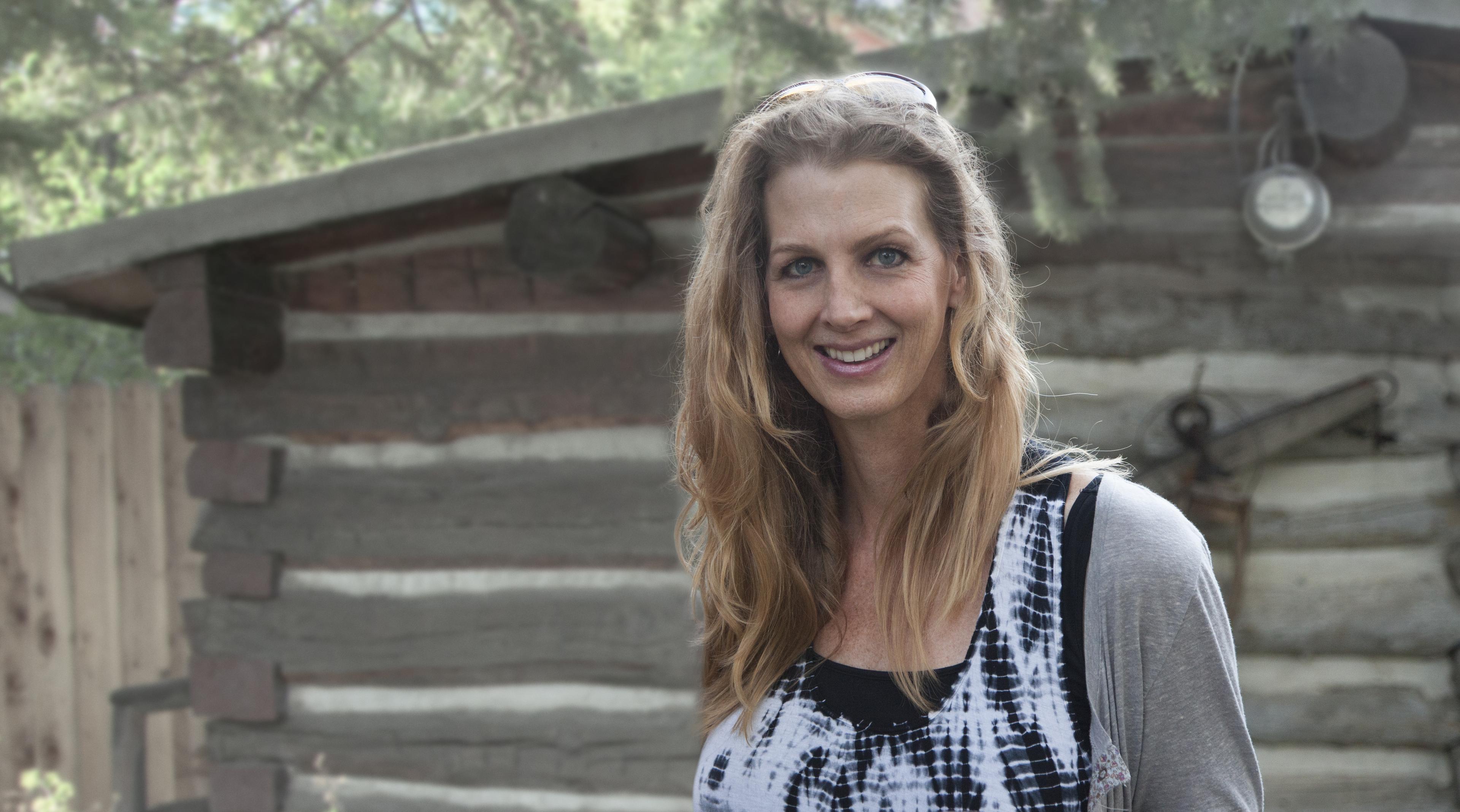 Kimberly Reed smiles at the camera infront of a wood structure.