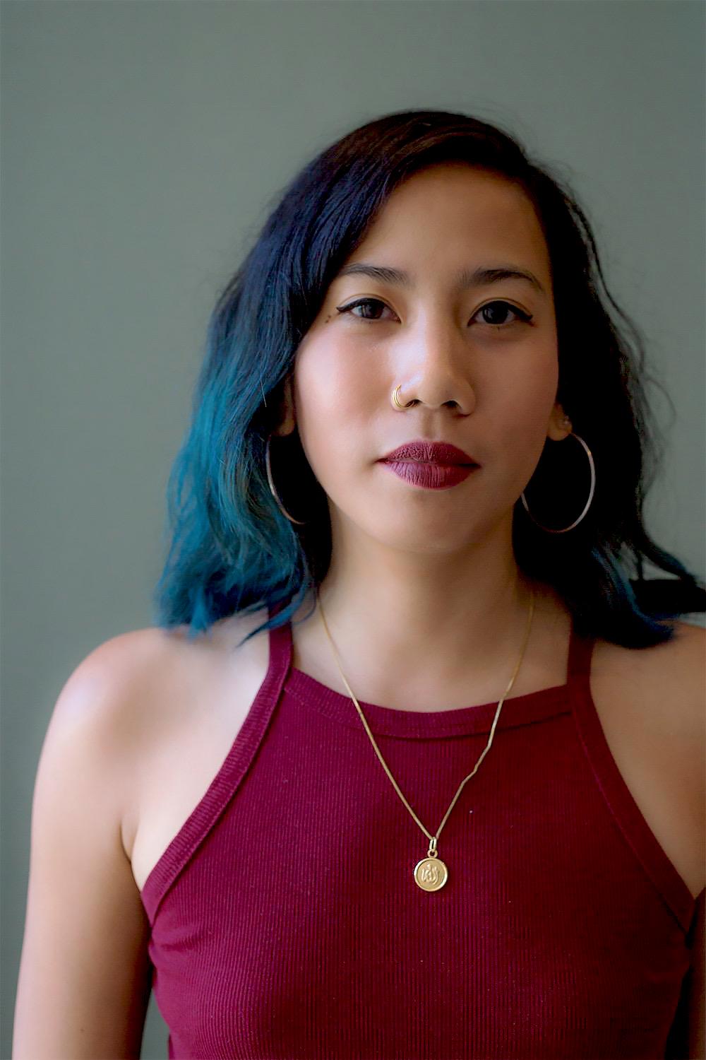 A portrait of Grace Pimentel Simbulan in front of a turquoise background.