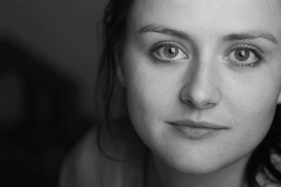 Cressida Trew looks directly at the camera with a slight smile . The photo is in black and white.