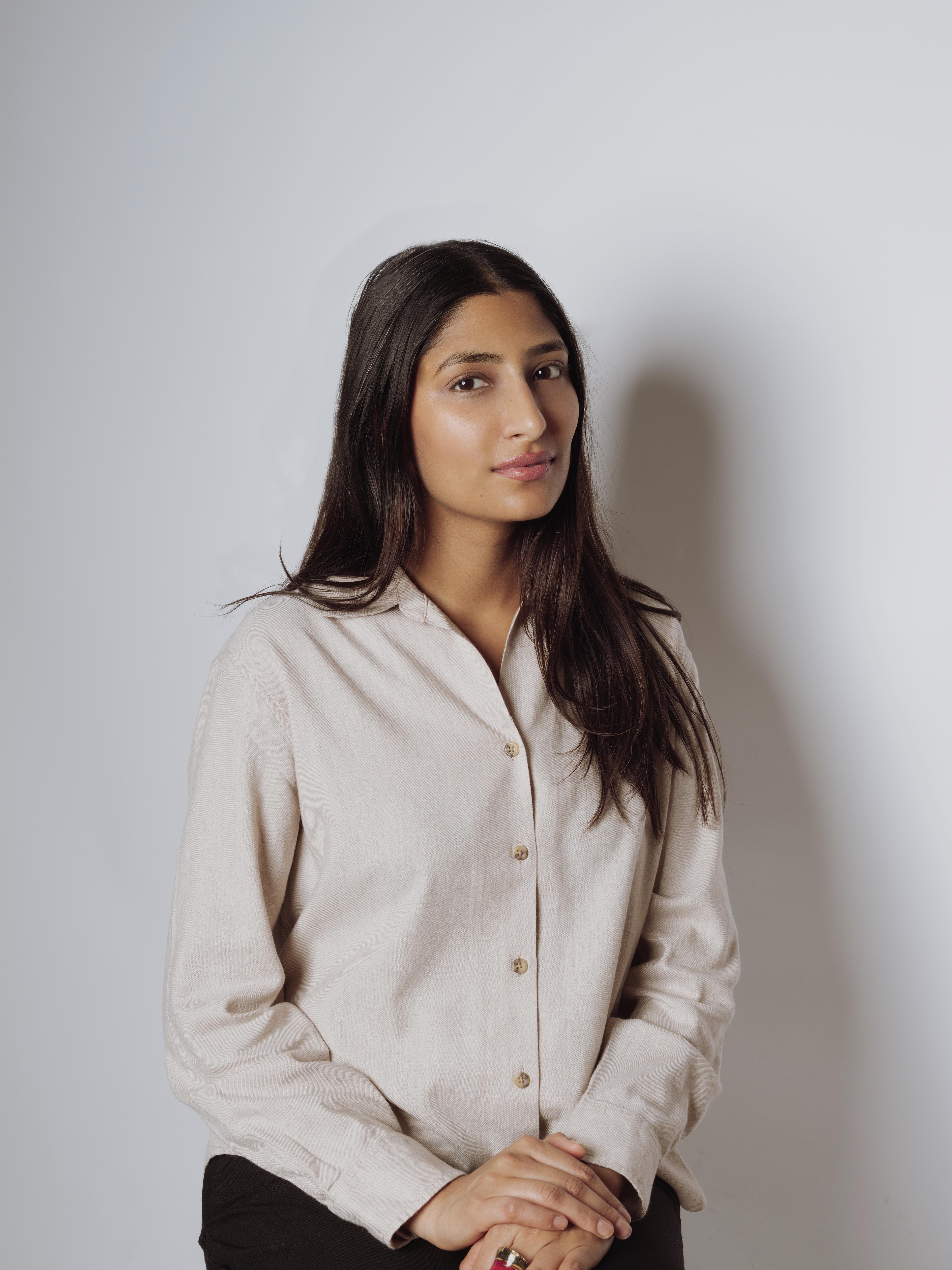 Headshot of Director Sara Chisht, seated in a light-colored shirt against a plain background.