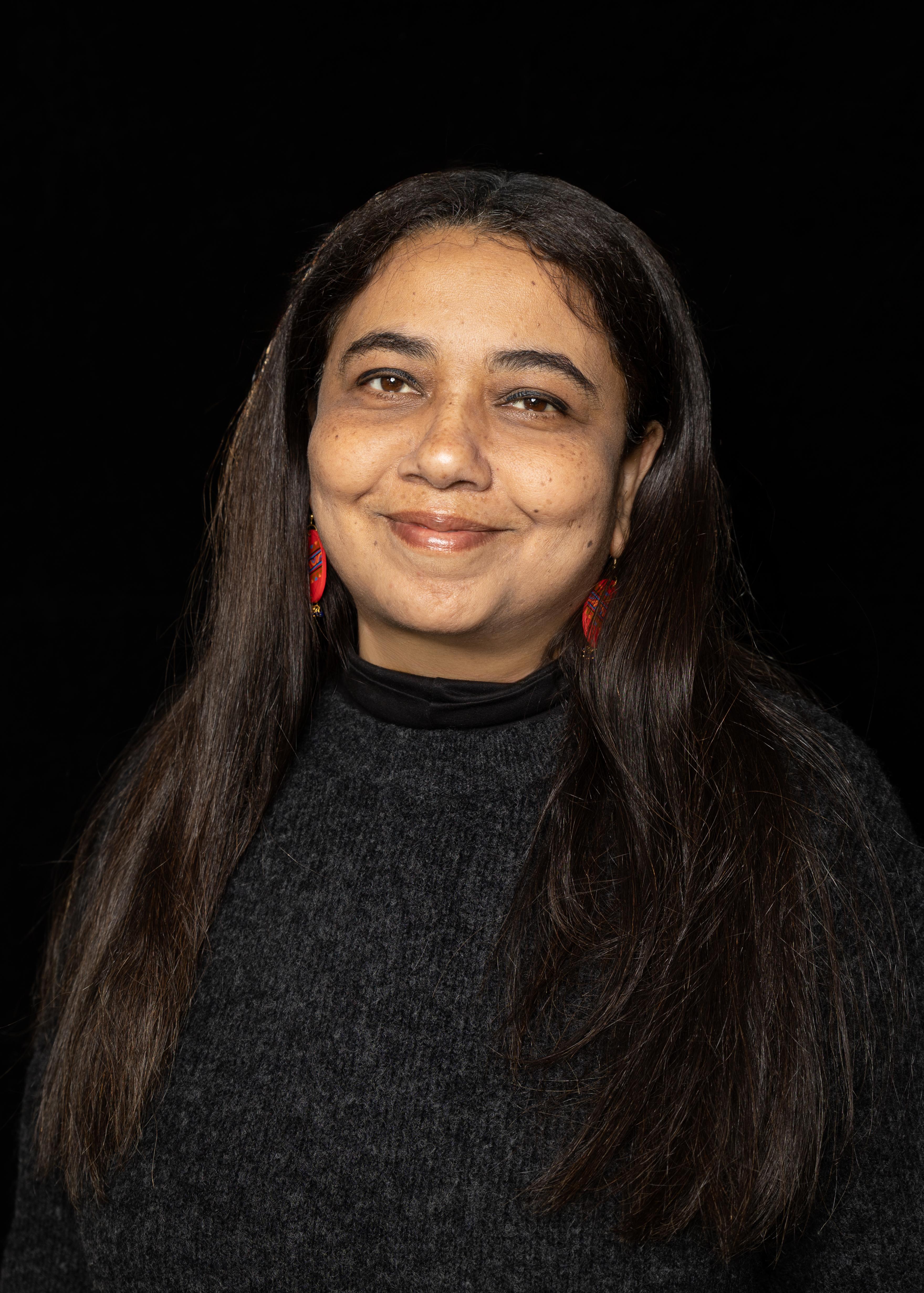 A portrait of a woman with dark hair smiling and looking past the camera.